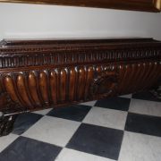 Coffre en bois sombre sculpté en forme de sarcophage, avec panneaux cannelés et pieds griffes
